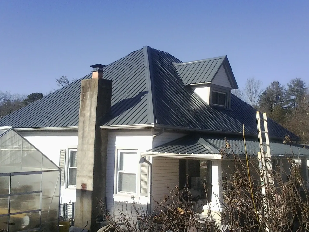Dark blue standing seam metal roof on a white farmhouse with dormer — Slate & Tile Roof Repair by Roofing Brothers in Checotah