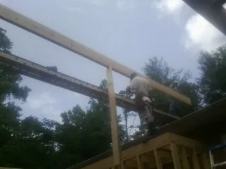Carpenter setting a ridge beam over a new addition frame — Ice Dam Removal by Roofing Brothers in Checotah