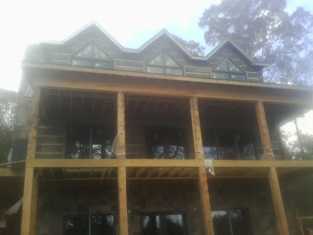 Dormers and porch framing on a large log home under construction — Roof Coating work by our crew in Checotah