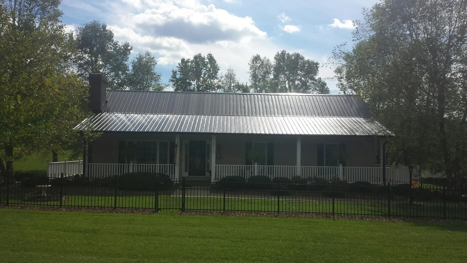 Gray metal roof on a brick ranch with a full width front porch — Gutter Guard Installation work by our crew in Checotah