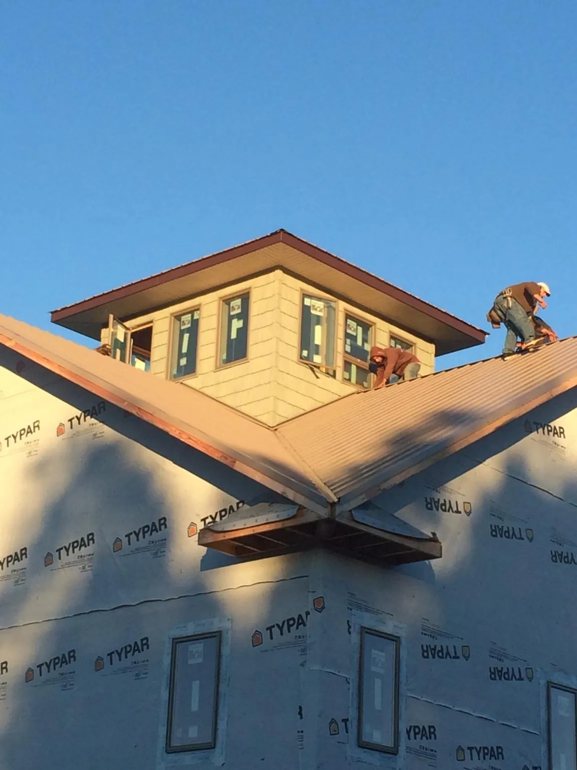 Roofers working around a rooftop cupola on a new metal roof at sunset — Roof Waterproofing in Checotah by Roofing Brothers